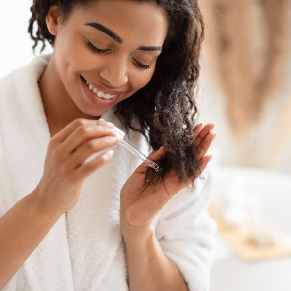 african-american-woman-applying-serum-on-damaged-hair-in-bathroom-1322880152-6847c28322db43129bca3aadf8f1d666.jpg